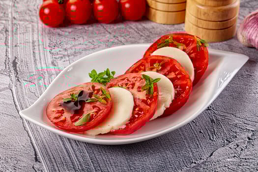 A plate of sliced tomatoes and cheese on a table photo