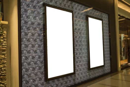 Two blank white billboards are displayed in a shopping mall photo