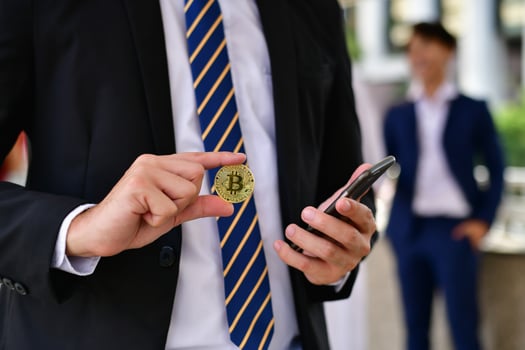 A man in a suit holding a bitcoin photo