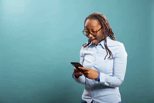Shocked black woman staring at her smartphone, with mouth wide open, reacting to wonderful news. Excited african american lady, checking her mobile device, receiving surprising message, lottery win. photo