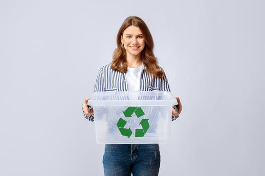 Smiling Young Woman Holding Empty Plastic Container With Green Recycle Sign Icon, Positive Millennial Woman Enjoying Zero Waste Living And Garbage Sorting, Standing Over Light Background, Copy Space photo