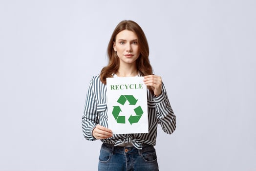 Recycling Concept. Young Beautiful Lady Demonstrating Placard With Green Recycle Sign, Millennial Eco-Friendly Nature-Lover Woman Standing Over Grey Studio Background, Looking At Camera, Copy Space photo