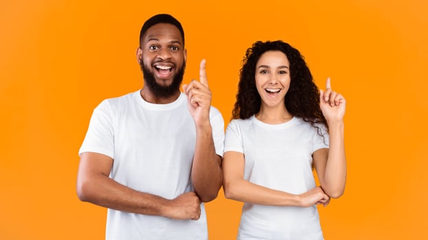 Happy couple pointing against orange background photo
