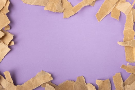 Brown torn craft paper strips frame on purple surface background photo