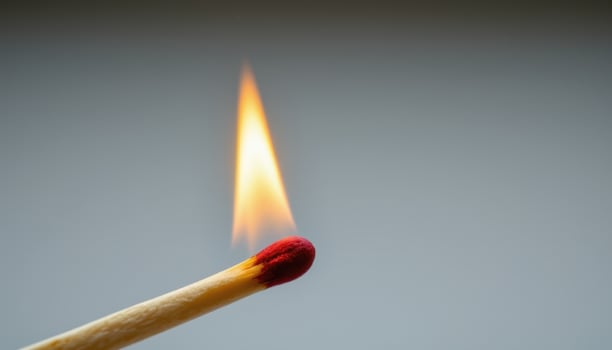 close up view of a slow burning matchstick with the flame engulfing the wood from the tip. photo
