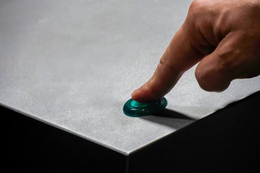 finger pressing a green illuminated button on metal isolated detail close up photo