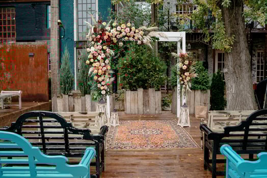 Elegant outdoor wedding ceremony venue with floral arch and rug in rustic garden setting photo
