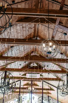 Rustic ceiling with exposed wooden beams and chandeliers decorated with string lights photo