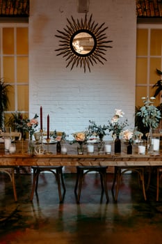 Elegant dining setup with floral centerpieces and sunburst mirror in rustic setting photo