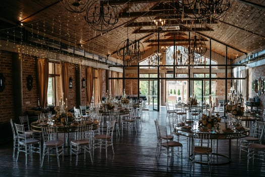 Elegant rustic wedding venue with round tables and chandeliers photo