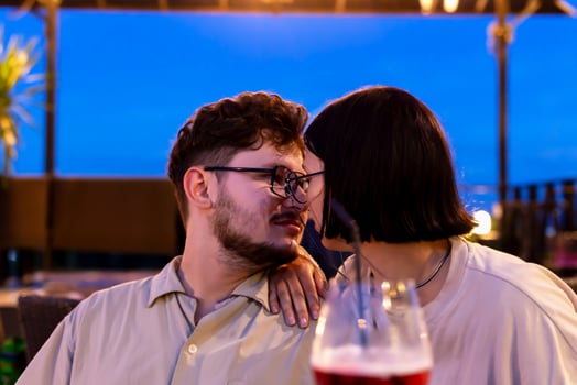 Romantic date on restaurant terrace at sunset. Romantic couple enjoying tender moment together at sunset, surrounded by cozy outdoor atmosphere, with drinks and evening sky creating warm ambiance photo