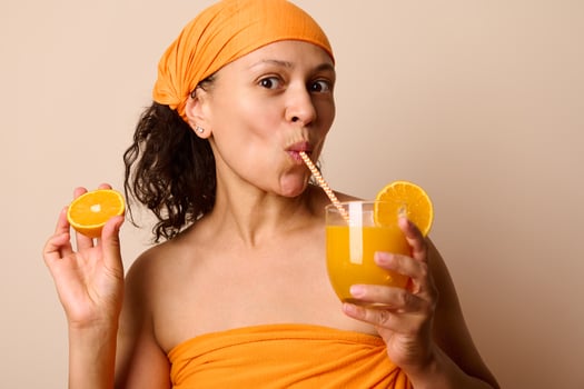 Refreshing Portrait of a Woman Enjoying Orange Juice While Holding Fresh Orange Slices photo