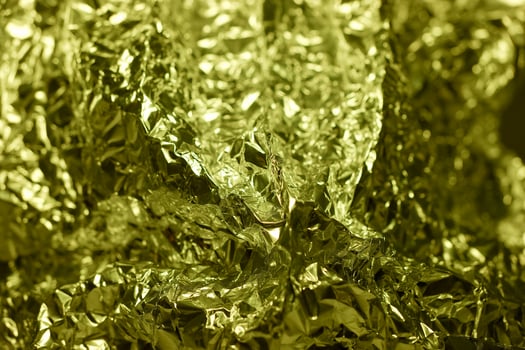 Shiny golden foil crumpled texture illuminated in bright light creating a vibrant, reflective surface photo