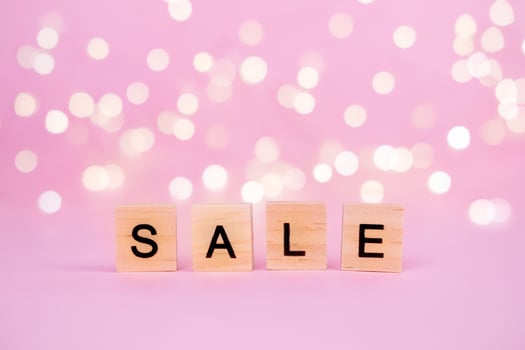 Words Sale on a blurred pink background with beautiful bokeh garland lights. With copyspace Concept of holidays christmas, valentine's day, black friday, mothers day and seasonal discounts photo