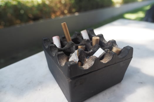 Ashtray filled with cigarette butts on an outdoor table photo