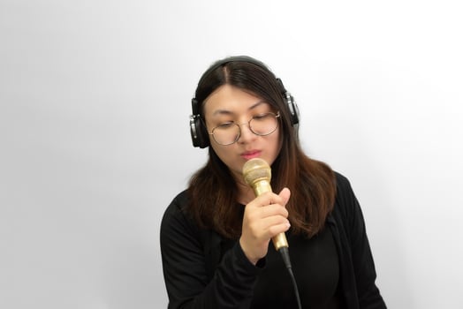 A woman with glasses and headphones holding a microphone photo