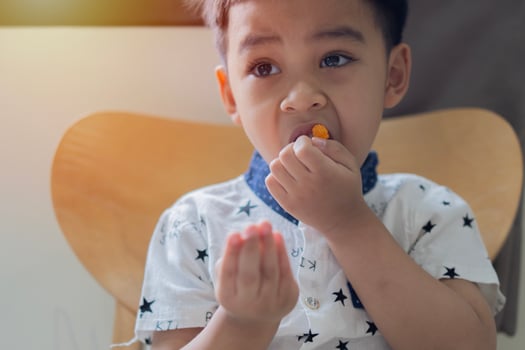 Portrait image of small Asian child, boy 3 years old wants to eat gelatinous sweets. photo