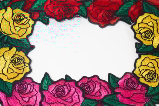Horizontal embroidery art of three roses in pink, red, and yellow thread, placed around white background edges with central copy space. Perfect for love, romance, and Valentine Day design. photo