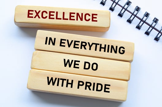 Excellence in everything we do with pride text on wooden blocks and notebook reflects unwavering quality and pride in every action photo