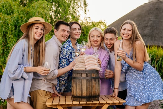 Happy friends drinking beer and enjoying each other company at a BBQ dinner in nature, with sausages on the table waiting to be grilled. Concept food and friendship, promoting BBQ photo