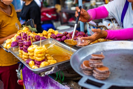 street vendor prepares Thai sweets including fried bananas and purple yams, offering a taste of local cuisine photo