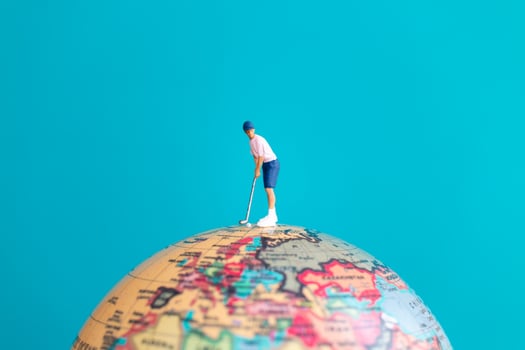A miniature figure of a golfer playing on top of a globe photo