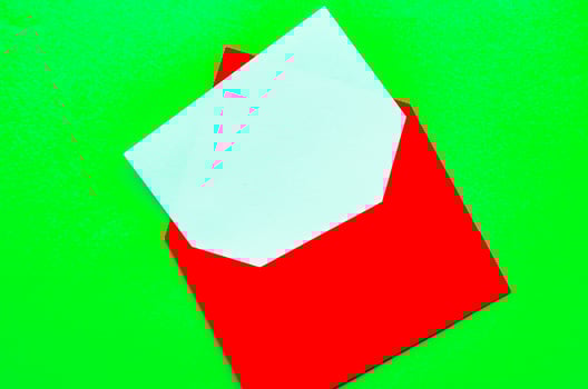 Top view of white notepad with envelope on green cover background with customizable space for text or ideas photo