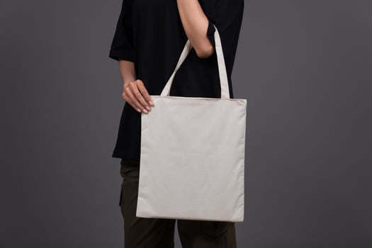 Front View of Female Holding Blank Canvas Tote Bag, Eco-Friendly Reusable Fabric with Handle, Close-Up Mockup, No Plastic and Environmental Concept photo