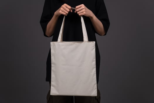 Front View of Woman Holding Blank Canvas Tote Bag, Eco-Friendly Reusable Fabric with Handle, Close-Up Mockup, No Plastic and Environmental Concept Dark Background photo