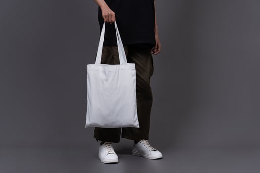 Front View of Woman Holding Blank Canvas Tote Bag, Eco-Friendly Reusable Fabric with Handle, Close-Up Mockup, No Plastic and Environmental Concept Background photo