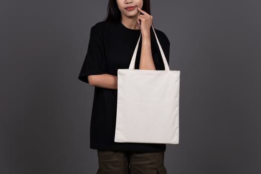 Front View of Woman Holding Blank Canvas Tote Bag, Eco-Friendly Reusable Fabric with Handle, Close-Up Mockup, No Plastic Concept photo