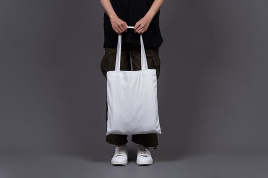Front View of Woman Holding Blank Canvas Tote Bag, Eco-Friendly Reusable Fabric with Handle, Close-Up Mockup, No Plastic and Environmental Concept photo
