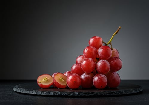 Fresh red grapes on a dark slate plate against a minimalist gray background photo