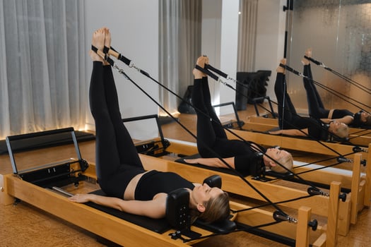 Woman practicing Pilates using reformer equipment in a bright studio during a midday session focusing on core strength and flexibility photo