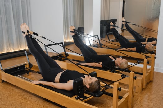 Pilates workout session featuring multiple individuals using reformer machines in a modern studio during afternoon hours photo