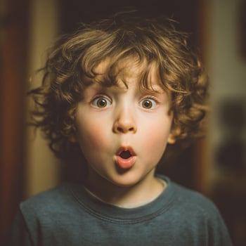 A surprised young boy with wide eyes and an open mouth stares in amazement. photo