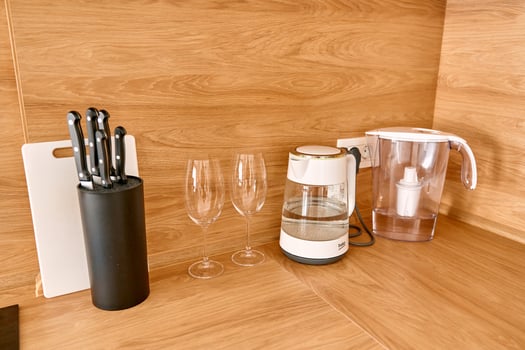 Modern kitchen countertop with coffee maker knives glasses and water filter photo
