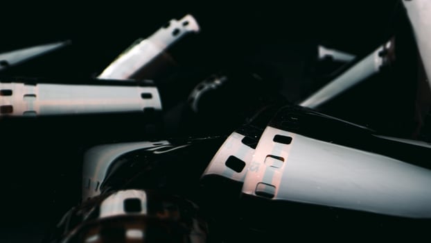 Photographic film isolated on a dark background, evoking a vintage and nostalgic feel. Close-up of a roll of film showing its perforated edges and smooth surface. photo
