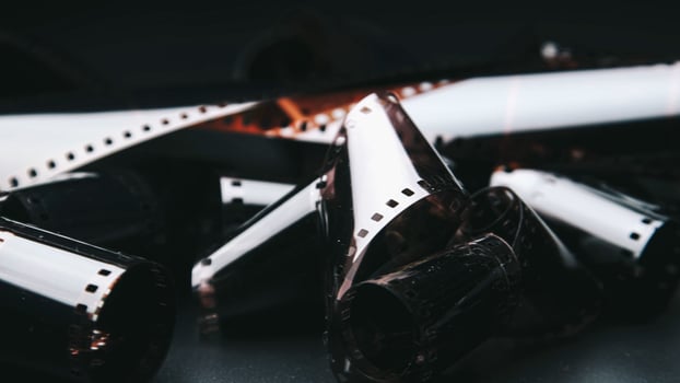 Photographic film isolated on a dark background, evoking a vintage and nostalgic feel. Close-up of a roll of film showing its perforated edges and smooth surface photo