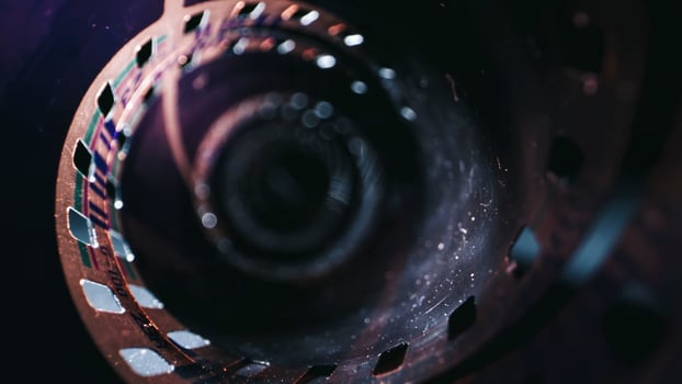 An old, rolled up color film lies on a dark background, symbolizing the memories captured on it. The film is aged, with faded colors in a retro style photo