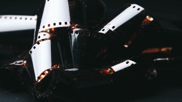 The film is aged, with faded colors. An old, rolled up color film lies on a dark background, symbolizing the memories imprinted on it. photo