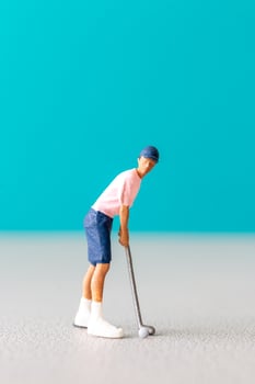 Miniature figurine of a golfer preparing to swing on a vibrant blue background. photo