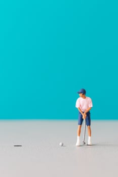 A Miniature figurine of a golfer preparing to swing on a vibrant blue background. photo
