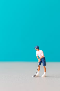 Miniature figurine of a golfer preparing to swing on a vibrant blue background photo