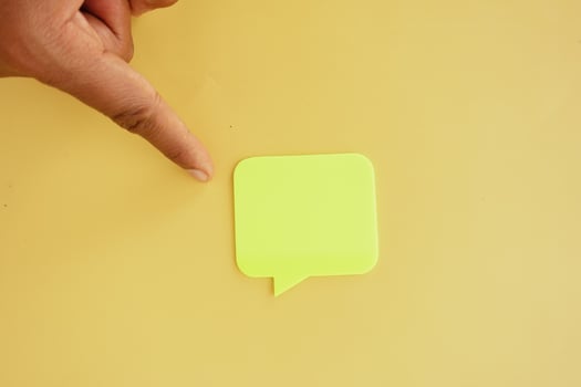 Hand pointing at green sticky note on yellow background photo