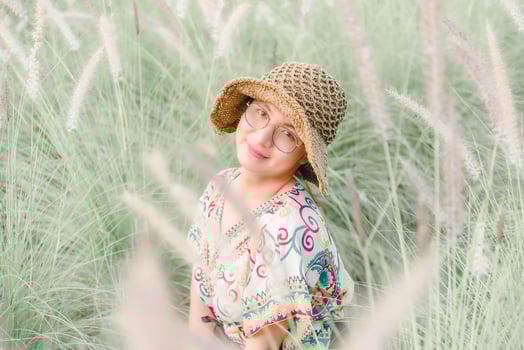 A girl in a hat and glasses in tall grass photo