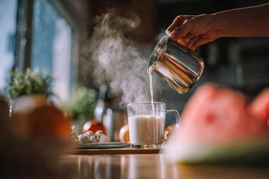 Pouring hot drink into mug at kitchen in the morning photo