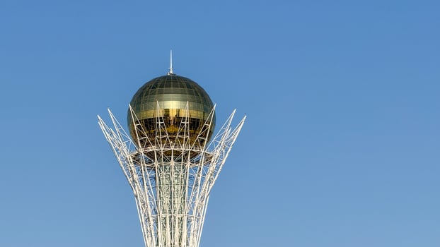 Golden sphere atop futuristic lattice tower, symbolizing cosmic unity Nauryz celebration, architectural wonder, celestial aspiration under azure skies photo