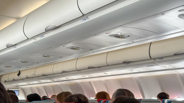 Rows of travelers nestled under aircraft overhead bins evoke wanderlusts whisper, hinting at World Tourism Days airborne adventures photo