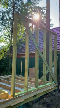 Rays of sunlight pierce through budding timber frame, whispering tales of eco homes and solstice celebrations in rustic harmony photo